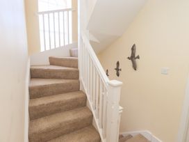 A carpeted staircase with white banisters and bird decorations on the wall at 4 Martindales Yard in Kendal