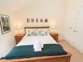 A bedroom with a wooden bed and bedside tables lamps and decorative pillows at 4 Martindales Yard in Kendal