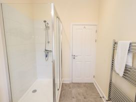 A bathroom with a glass shower enclosure a white door and a metal towel rack with a towel at 4 Martindales Yard in Kendal