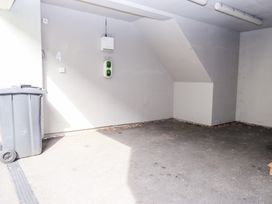 A parking space with a gray trash bin and electrical outlets on the wall at 4 Martindales Yard in Kendal
