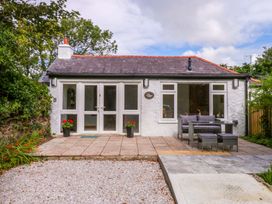 A cottage with patio seating and flower pots at Cromlech Cottage at Cromlech Manor Farm near Tyn-y-Gongl
