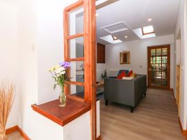 A living room with a sofa and flowers on a table at Cromlech Cottage at Cromlech Manor Farm Tyn-y-Gongl near Benllech