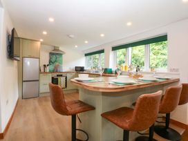 A kitchen with bar stools and tableware at Cromlech Cottage at Cromlech Manor Farm near Benllech