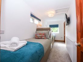 A bedroom with two beds and a television at Cromlech Cottage at Cromlech Manor Farm near Benllech