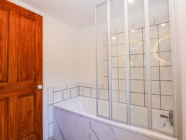 A bathroom with a bathtub and shower screen at Cromlech Cottage at Cromlech Manor Farm in Tyn-y-Gongl near Benllech