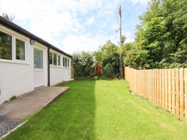 A garden with grass and a wooden fence at Cromlech Cottage at Cromlech Manor Farm near Tyn-y-Gongl
