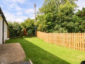A garden with grass and a wooden fence at Cromlech Cottage at Cromlech Manor Farm, Tyn-y-Gongl near Benllech