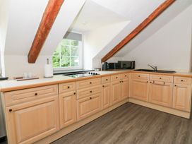 A kitchen with wood cabinets and appliances at Loft apartment in Llandysul