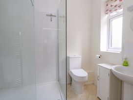 A bathroom with a shower, toilet, sink and storage cabinet at 1 Fernhill Avenue Weymouth
