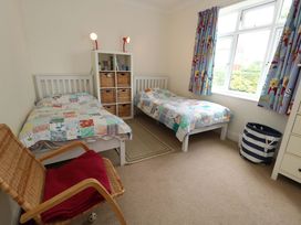 A bedroom with two beds and a bookcase at 1 Fernhill Avenue in Weymouth