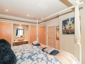 A bedroom with a bed and a mirror at Yarn Cottage in Broadway