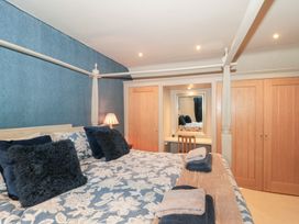 A bedroom with a double bed and a mirror at Yarn Cottage in Broadway