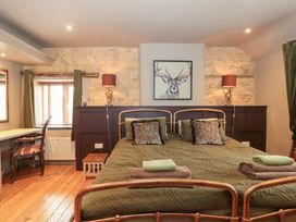 A bedroom with a bed and desk at Yarn Cottage in Broadway