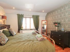A bedroom with a bed and mirror at Yarn Cottage in Broadway