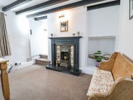 A room with a fireplace a wooden bench with a cushion a small plant in a niche and a step leading to a door at Bwthyn Llwyncaron in Rhydtalog near Llandegla