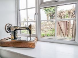An antique sewing machine on a white windowsill with a garden and stone wall visible outside Bwthyn Llwyncaron Rhydtalog near Llandegla