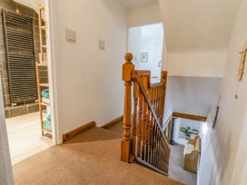 A carpeted stairway with wooden banister and a hallway leading to a bathroom and a living room at Bwthyn Llwyncaron in Rhytalog near Llandegla