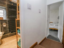 A hallway with doors leading to a bathroom with wooden shelves and a bedroom with a bed at Bwthyn Llwyncaron in Rhydtalog near Llandegla