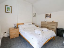 A bedroom with a double bed two bedside tables a chest of drawers and framed pictures on the walls at Bwthyn Llwyncaron in Rhydtalog near Llandegla