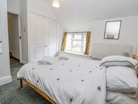 A bedroom with a bed and white bedding with bee patterns near a window with yellow curtains at Bwthyn Llwyncaron in Rhydtalog near Llandegla