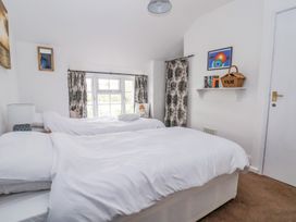 A bedroom with two single beds with white bedding and a window with patterned curtains at Bwthyn Llwyncaron in Rhydtalog near Llandegla