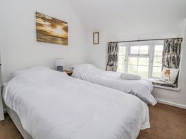 A bedroom with two single beds a side table with lamp and a window seat with curtains and a pillow at Bwthyn Llwyncaron Rhydtalog near Llandegla