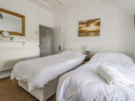 A bedroom with two single beds white bedding and a lamp on a bedside table at Bwthyn Llwyncaron in Rhydtalog near Llandegla