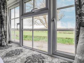 A window with open handles overlooking a road and green fields at Bwthyn Llwyncaron in Rhydtalog near Llandegla