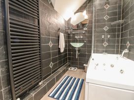 A bathroom with a bathtub a glass sink a towel hanging on a rail and a striped rug on the floor at Bwthyn Llwyncaron in Rhydtalog near Llandegla