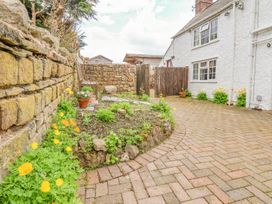 A garden area with flowers and a stone wall next to a white house at Bwthyn Llwyncaron in Rhydtalog near Llandegla
