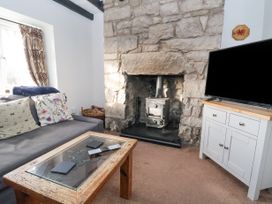 A living room with a stone fireplace a wood stove a grey sofa and a wooden coffee table at Bwthyn Llwyncaron Rhydtalog near Llandegla