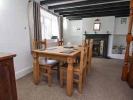 A dining room with a wooden table and chairs near a window and a fireplace at Bwthyn Llwyncaron Rhydtalog near Llandegla