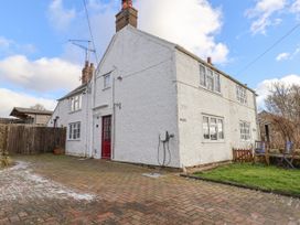 A white two story house with red door and brick driveway with wooden chairs and table on grass at Bwthyn Llwyncaron in Rhydtalog near Llandegla
