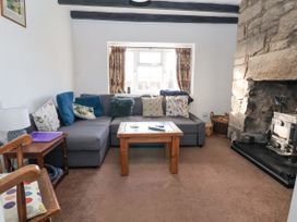 A living room with a gray sectional sofa and floral cushions beside a stone fireplace at Bwthyn Llwyncaron in Rhydtalog near Llandegla