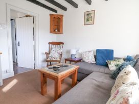 A sitting room with a gray sofa cushions a wooden chair and a wooden coffee table at Bwthyn Llwyncaron in Rhydtalog near Llandegla