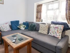 A sitting area with a gray sectional sofa with patterned and textured cushions and a wooden coffee table with a glass top at Bwthyn Llwyncaron Rhydtalog near Llandegla