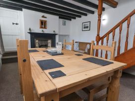 A dining area with a wooden table and chairs near a fireplace and staircase at Bwthyn Llwyncaron in Rhydtalog near Llandegla