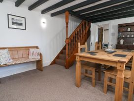 A dining area with a wooden table and chairs next to a staircase and a wooden bench with cushions at Bwthyn Llwyncaron Rhydtalog near Llandegla