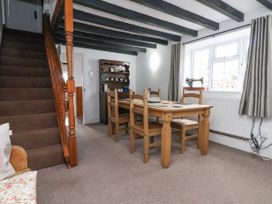 A dining room with wooden table and chairs next to a staircase and window at Bwthyn Llwyncaron in Rhydtalog near Llandegla