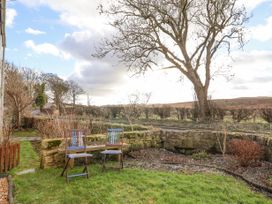 An outdoor garden area with two chairs on grass near a stone wall and trees at Bwthyn Llwyncaron in Rhydtalog near Llandegla