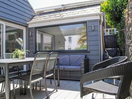 An outdoor patio area with a dining table and chairs and a cushioned wicker sofa at 2 Russell Court in Salcombe