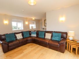 A living room with a sofa and windows at Belan Wen in Llanddona near Pentraeth