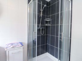 A shower with glass doors and towels in a bathroom at Belan Wen in Llanddona near Pentraeth