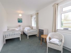 A bedroom with two beds and a chair at Belan Wen in Llanddona near Pentraeth