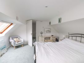 A bedroom with a bed, chair and mirror at Belan Wen in Llanddona near Pentraeth