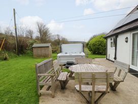 A garden with a table and benches near a hot tub at Belan Wen in Llanddona near Pentraeth