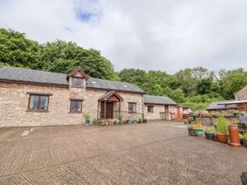 A stone house with multiple windows and potted plants along the entrance at Henblas Cottage in Rhyd-Y-Foel