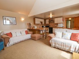 A living room with two sofas and kitchen area with wooden stools at Henblas Cottage in Rhyd-Y-Foel