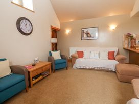 A living room with sofas chairs a coffee table a wall clock and a framed picture at Henblas Cottage in Rhyd-Y-Foel