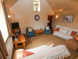 A living room with sofas armchairs a coffee table a wall clock and a television at Henblas Cottage in Rhyd-Y-Foel